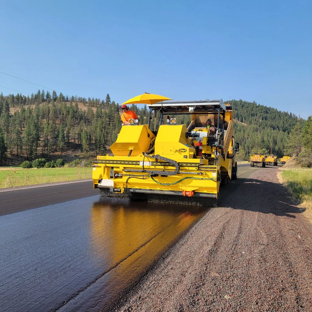 Sealcoat tanker spraying a fresh emulsion coat across a commercial lot